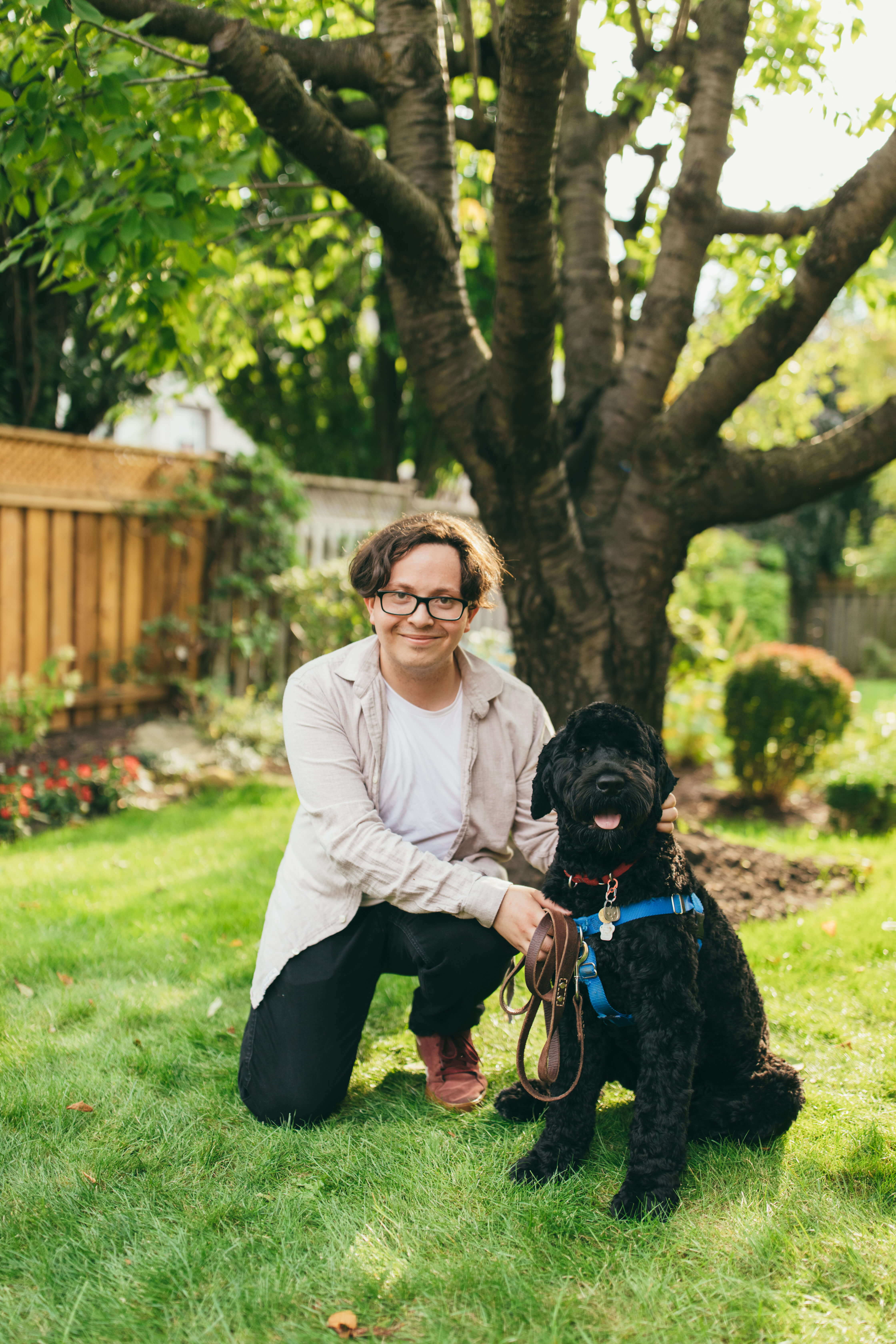 Corey Hamat kneeling next to a Portuguese Water Dog
